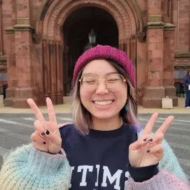 Cloud Osmond ’24 smiling making peace signs outside the Smithsonian