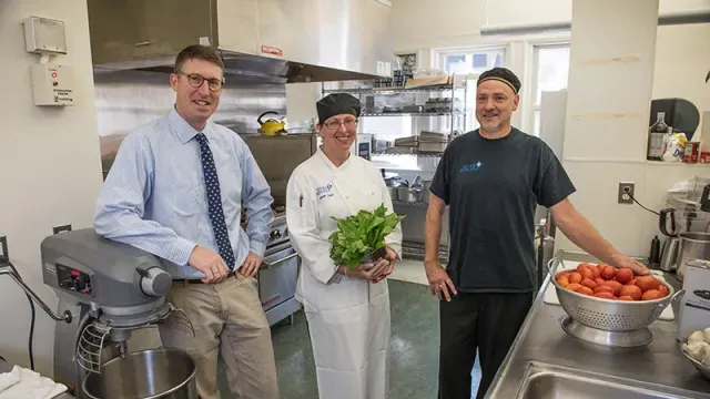 Andy Cox with two dining employees in one of the kitchens