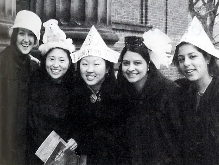 一群高年级学生站在约翰. 格林大厅，戴着帽子，穿着长袍.