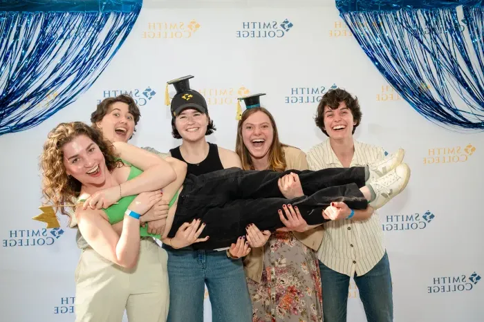 Four students hold up their friend at the senior soiree.